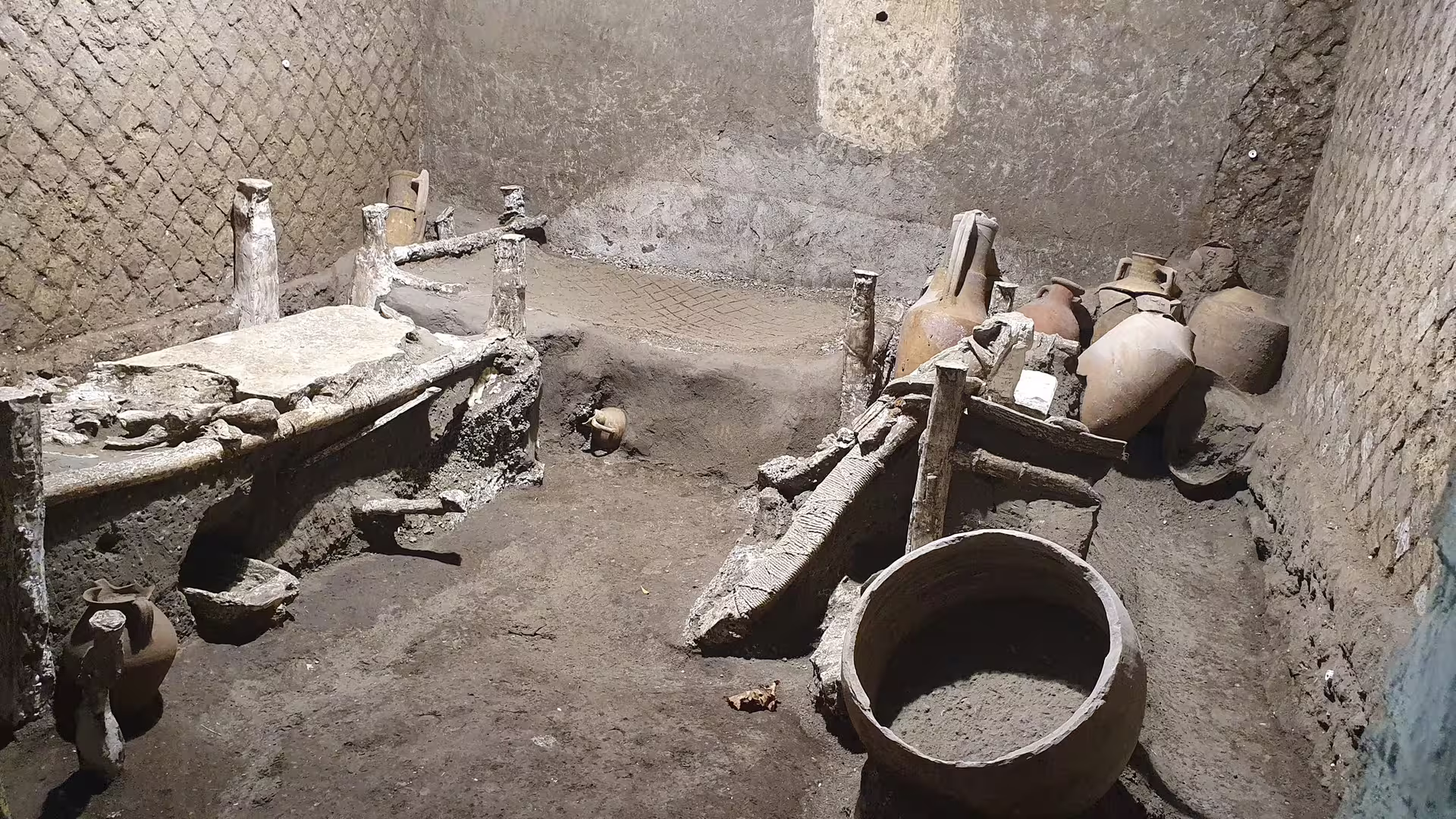 Herculaneum excavated room with ancient beds and amphorae, seen on Pompeii and Herculaneum group tour from Naples