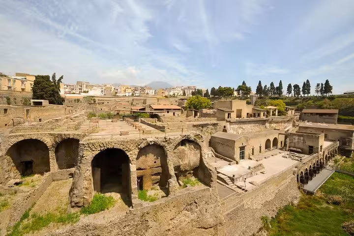 Ancient ruins of Herculaneum with arched structures and greenery, offering a glimpse into Roman history near Naples.