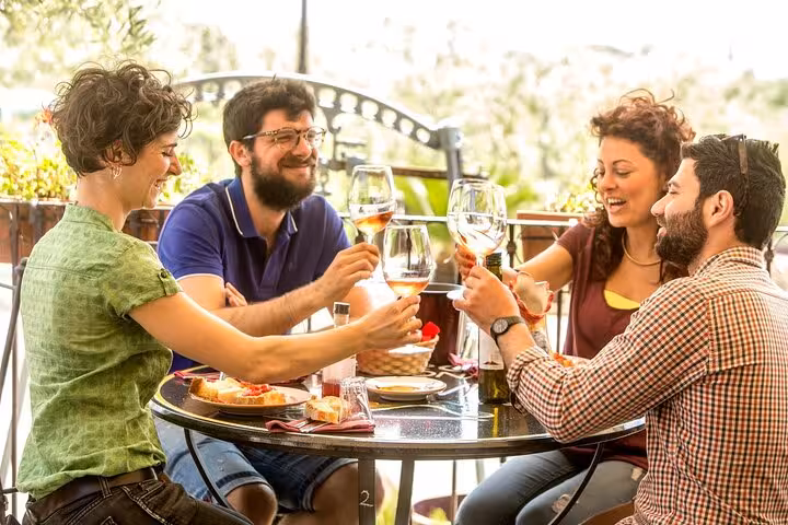 Group of friends enjoying a leisurely lunch with wine, included in the Herculaneum & Pompeii skip-the-line tour package.