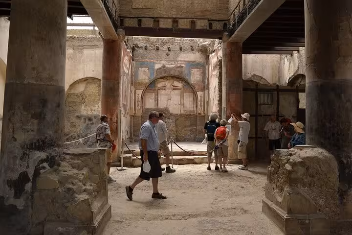 Visitors exploring the preserved ruins of a grand Roman villa in Herculaneum, highlighting cultural heritage on tours.