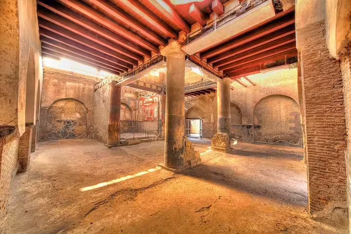 Herculaneum ruins interior with columns and frescoed walls, low cost guided tour from Naples day trip highlight