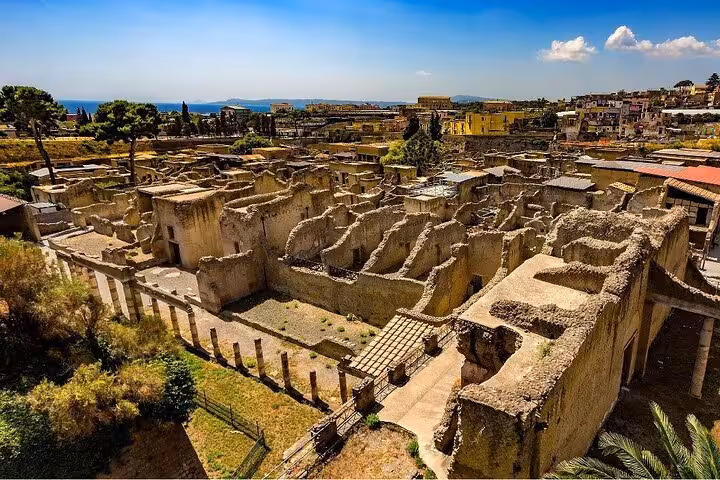 Panoramic view of Herculaneum ruins under a clear blue sky, highlighting ancient Roman structures and layout.