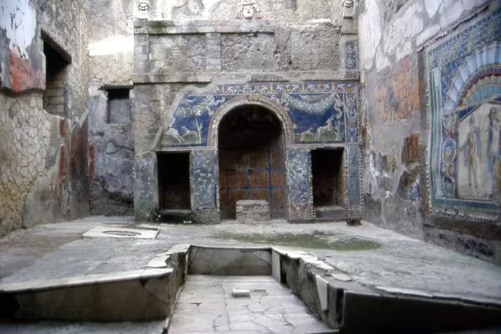 Intricate mosaics and frescoed walls surrounding an ancient Roman bath in Herculaneum ruins on a private half-day guided tour
