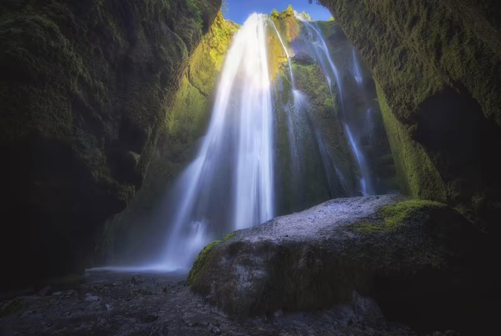 Hidden waterfall cascading inside a narrow mossy canyon on Iceland's South Coast