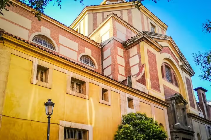 Historic yellow and red brick church building in Madrid under blue sky