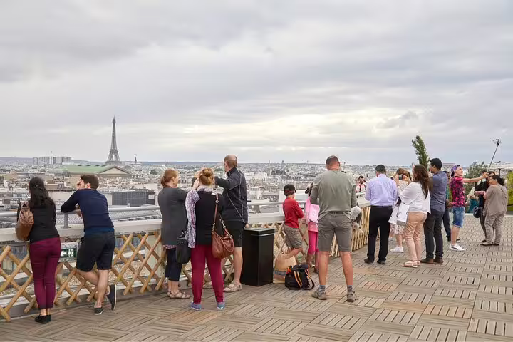 Tourists enjoy panoramic views of Paris from a rooftop terrace, highlighting hidden gems and secret spots in the city.