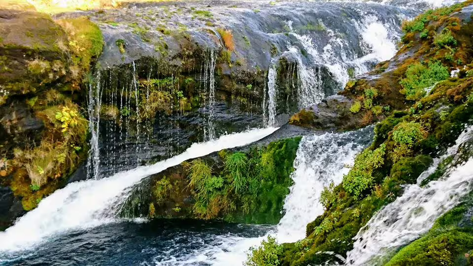 Cascading hidden waterfall with lush green moss-covered rocks on a private Super Jeep day trip Iceland