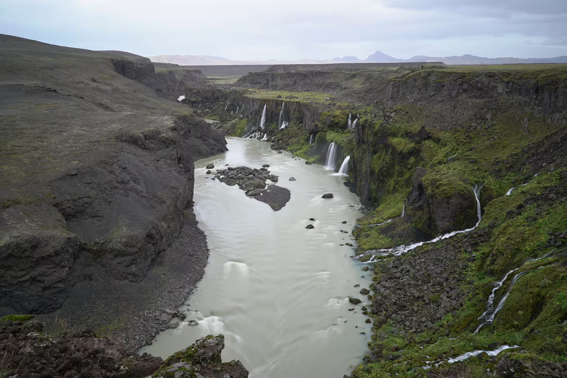 Multiple hidden waterfalls cascading into a green mossy Iceland canyon river discovered on a private super jeep day trip