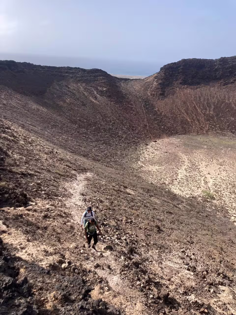 Hikers explore the rugged volcanic terrain of Viana Volcano, São Vicente, offering breathtaking views and adventure.