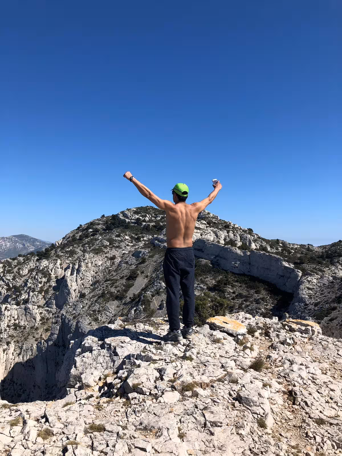 Hiker celebrating on a rocky summit in Calanques National Park on a 3-day Marseille hiking tour
