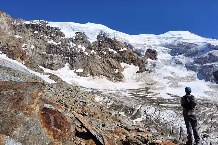 Hiker overlooking a glacier and rugged Swiss Alps ridgeline, a hidden gem stop on the 4-day Swiss Alps tour