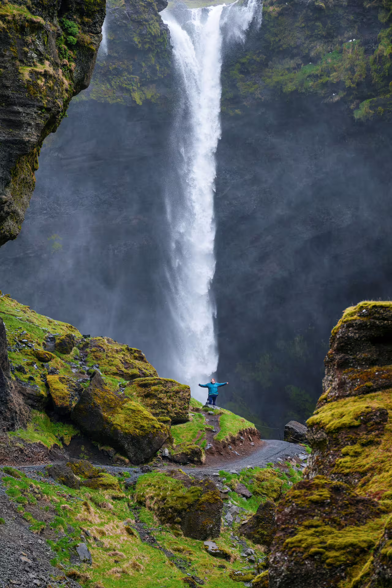 Hiker with arms wide open before towering Icelandic waterfall on Southeast Iceland Viking Journey