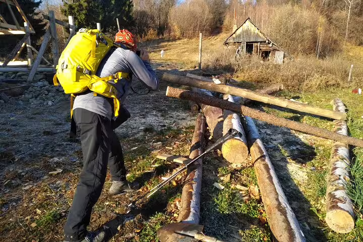 Hiker with yellow backpack and red helmet navigating log obstacles in Taga Mountains near Brasov