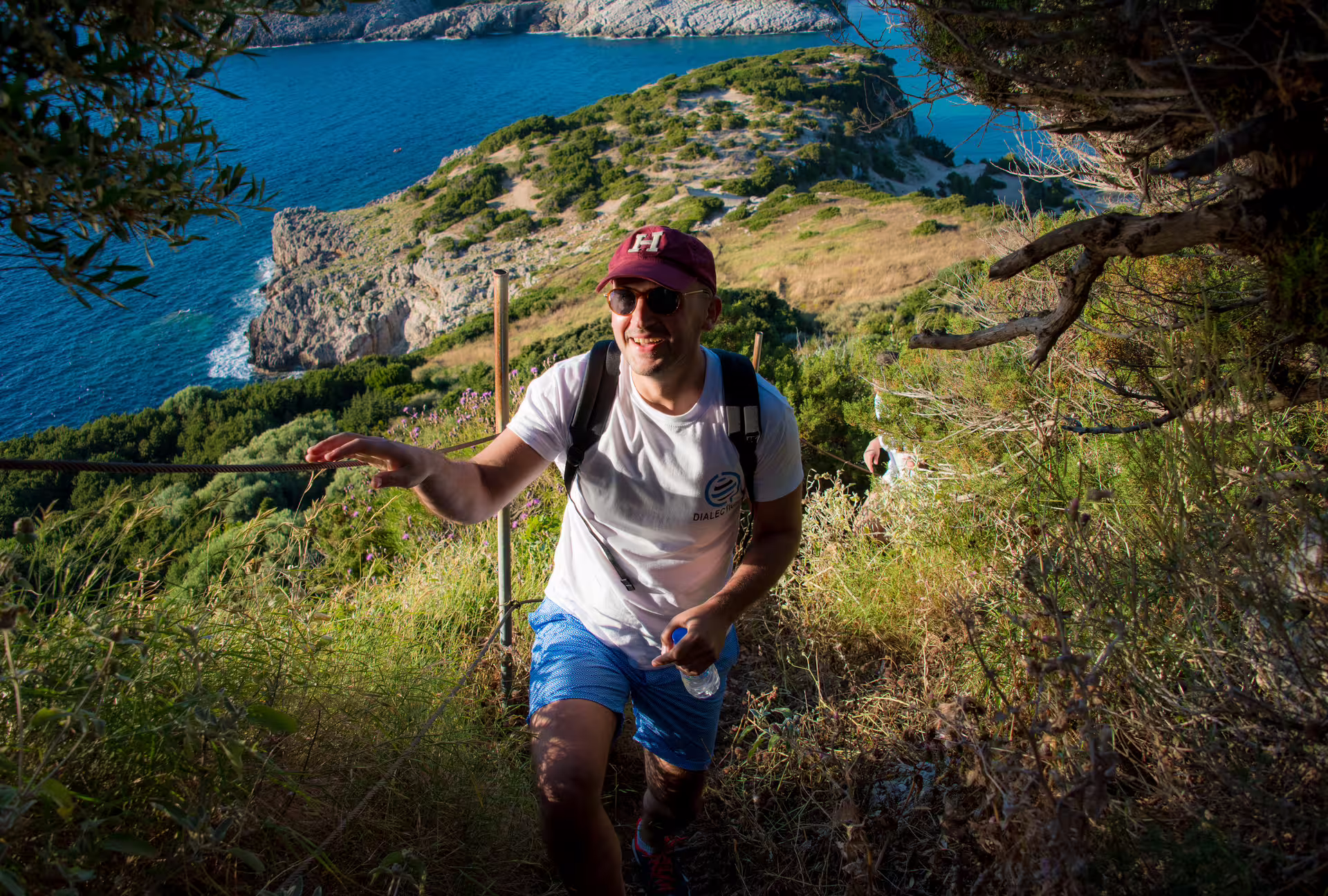 Hiker climbing coastal trail above Navarino Bay, Pylos, with sweeping sea views on guided hiking tour