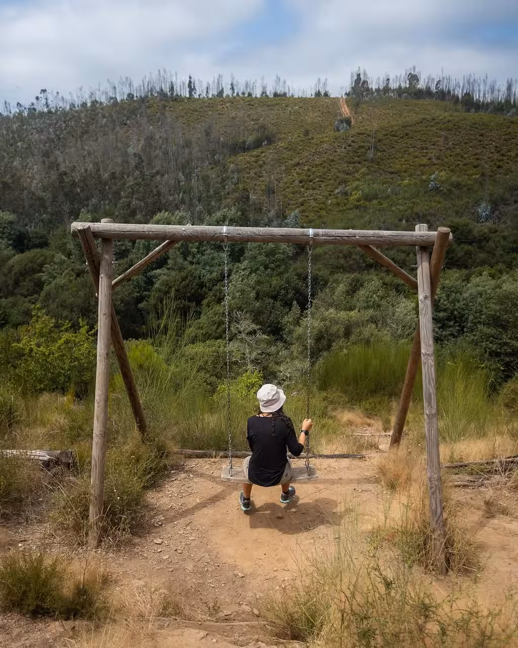 Hiker relaxing on a rustic swing with valley views during Jeeptour nature hike and outdoor yoga experience