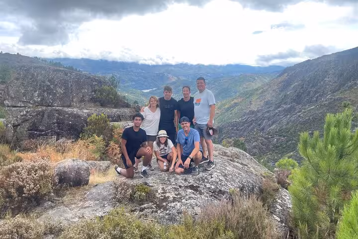 Group of hikers posing on a rocky viewpoint overlooking lush valleys in Geres National Park, ideal for nature exploration.