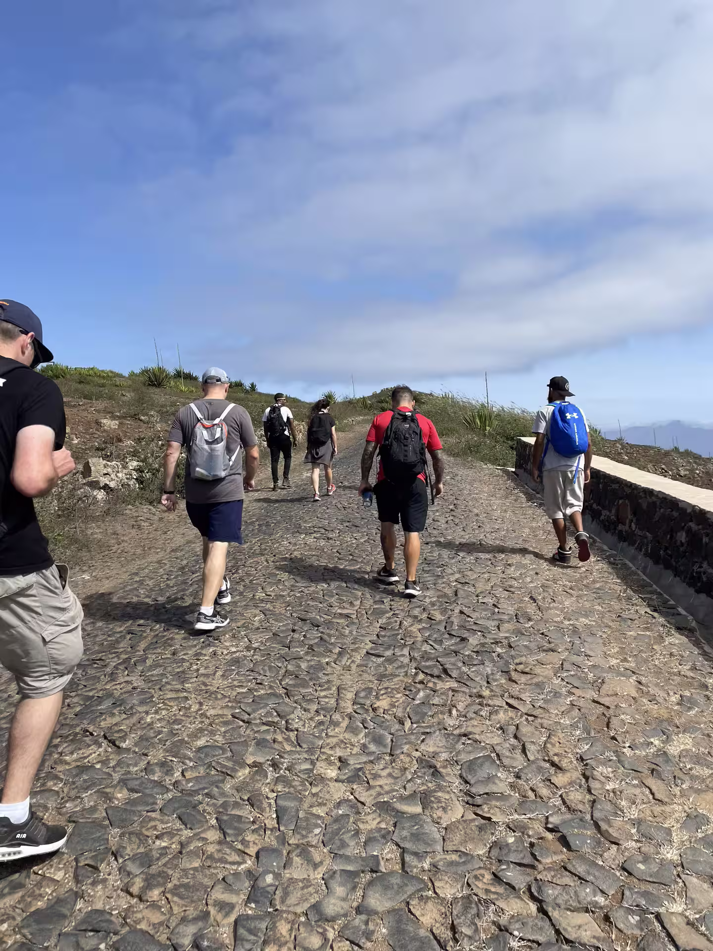 Group of hikers exploring the scenic cobblestone trails of Monte Verde, São Vicente under a clear blue sky.