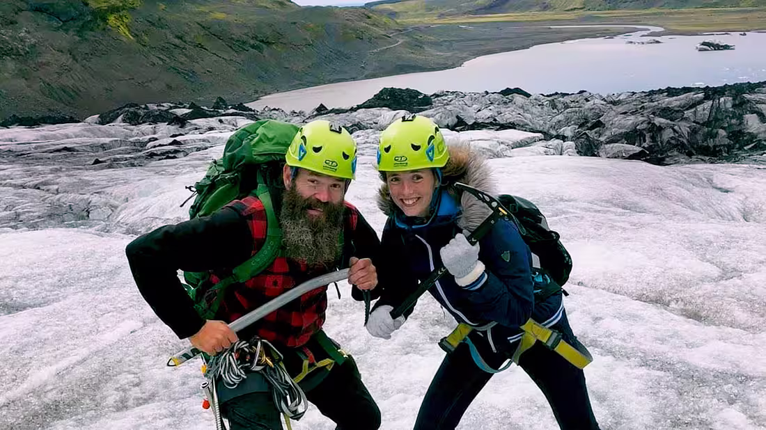 Two people in hiking gear posing for a photo atop a glacier