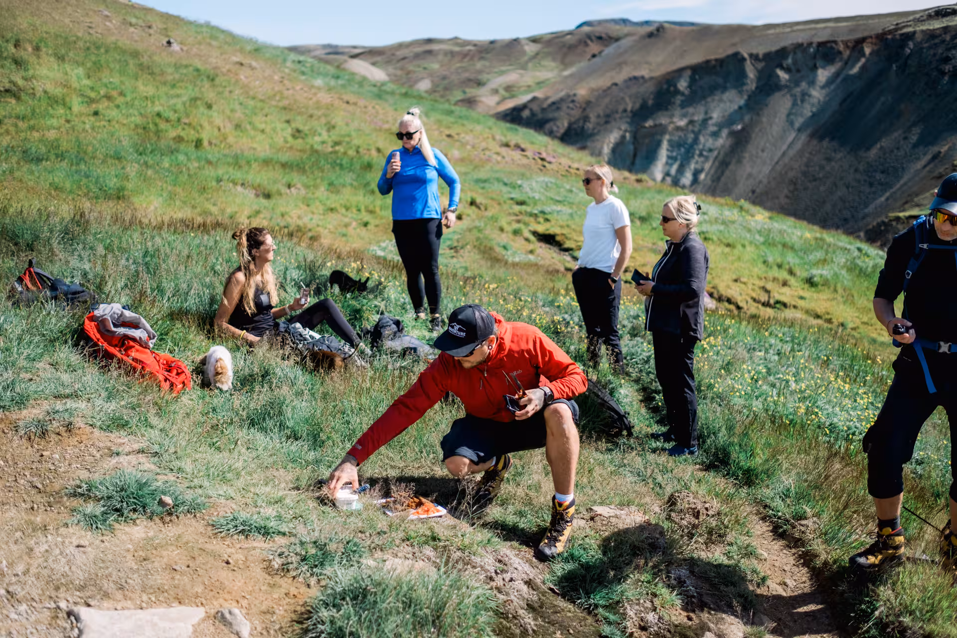 Hiking group taking a break on green volcanic hillside near Hengill Volcano, Iceland