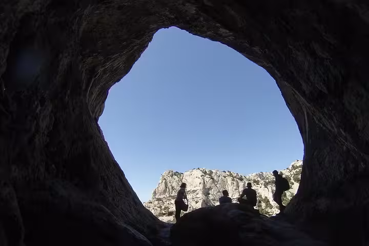 Hikers silhouetted in a sea cave opening, Calanques National Park near Marseille on a 3-day tour