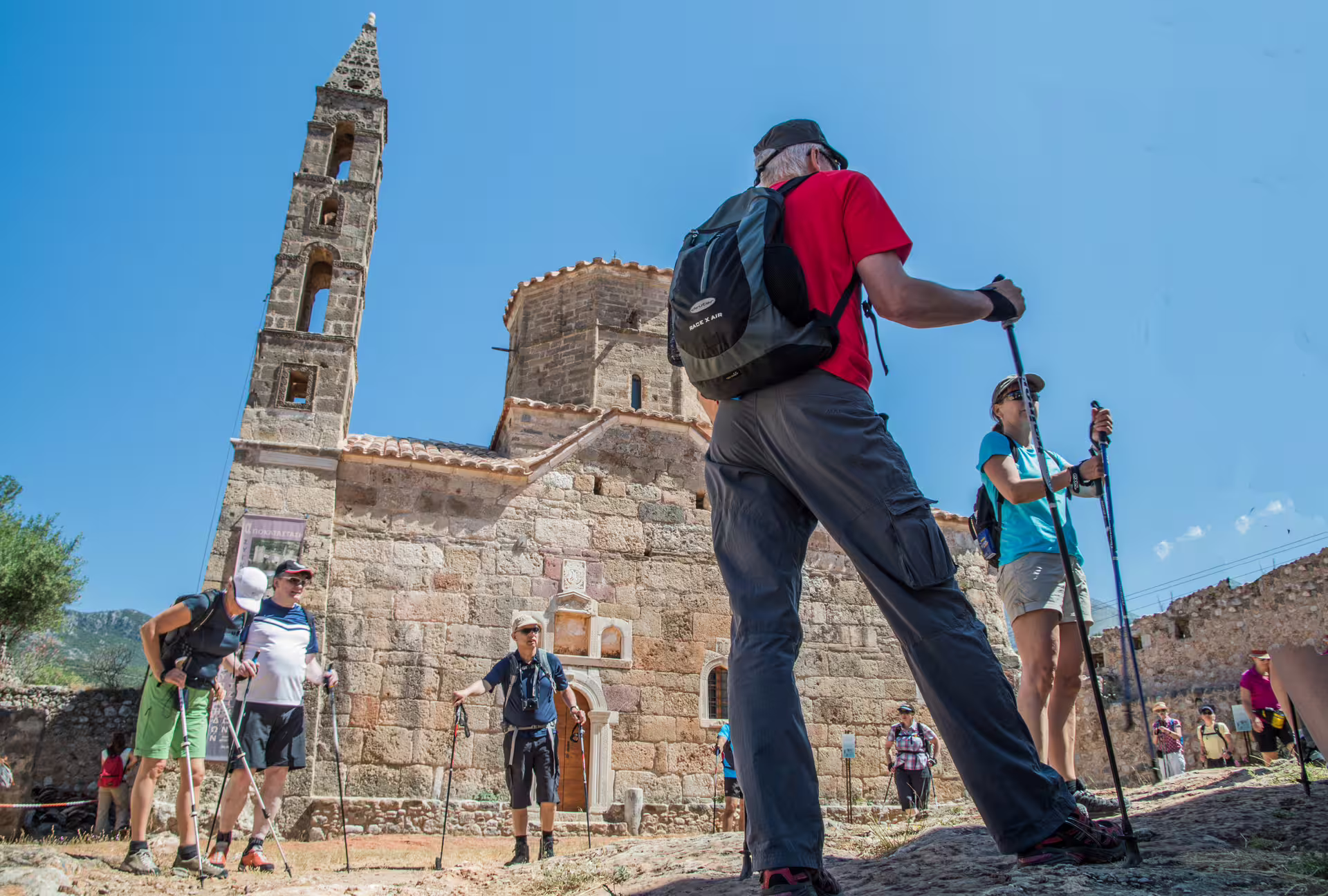 Hikers with trekking poles at historic stone church in Kardamyli, Mani Peninsula, Greece guided walking tour