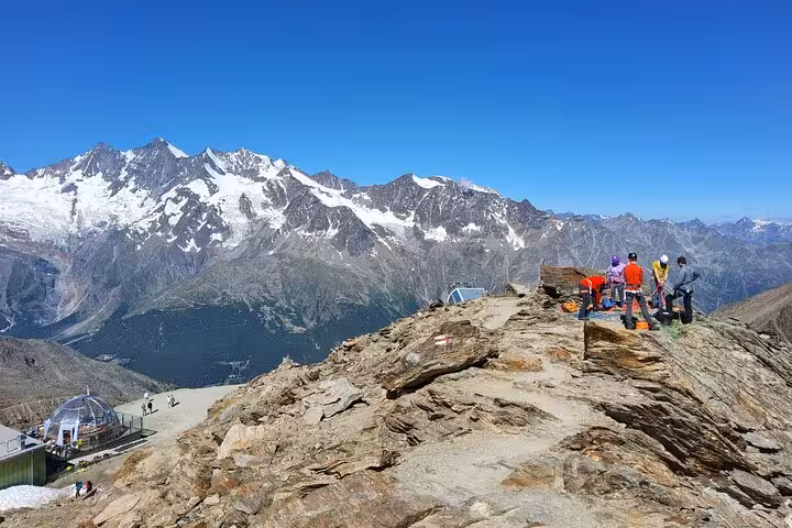 Hikers on rocky viewpoint above Zermatt with sweeping Swiss Alps panorama on a 4-day guided tour