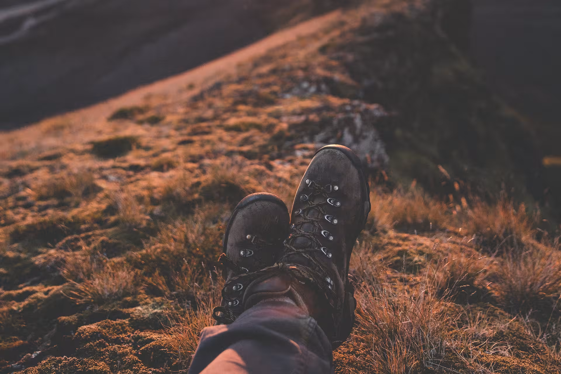 Hiker resting on mossy mountain terrain wearing worn leather hiking boots on Fimmvorduhals trail Iceland