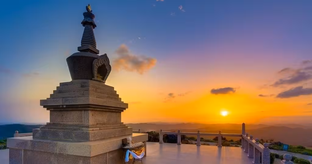Sunset over misty hills from a hilltop Buddhist-style stupa terrace on The Hills & Traditions Trail spiritual tour