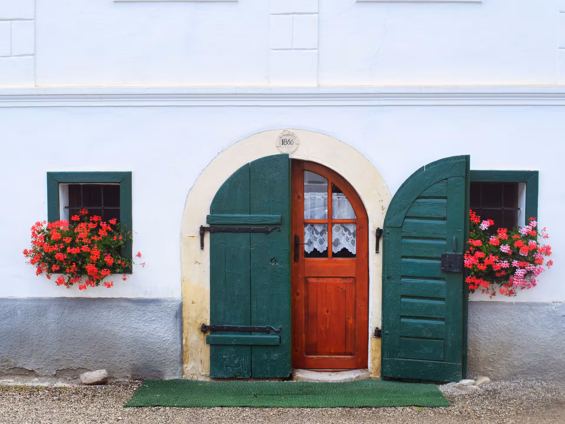 Historic 1866 traditional house with green shutters and red geraniums in Rimetea Apuseni Mountains Romania