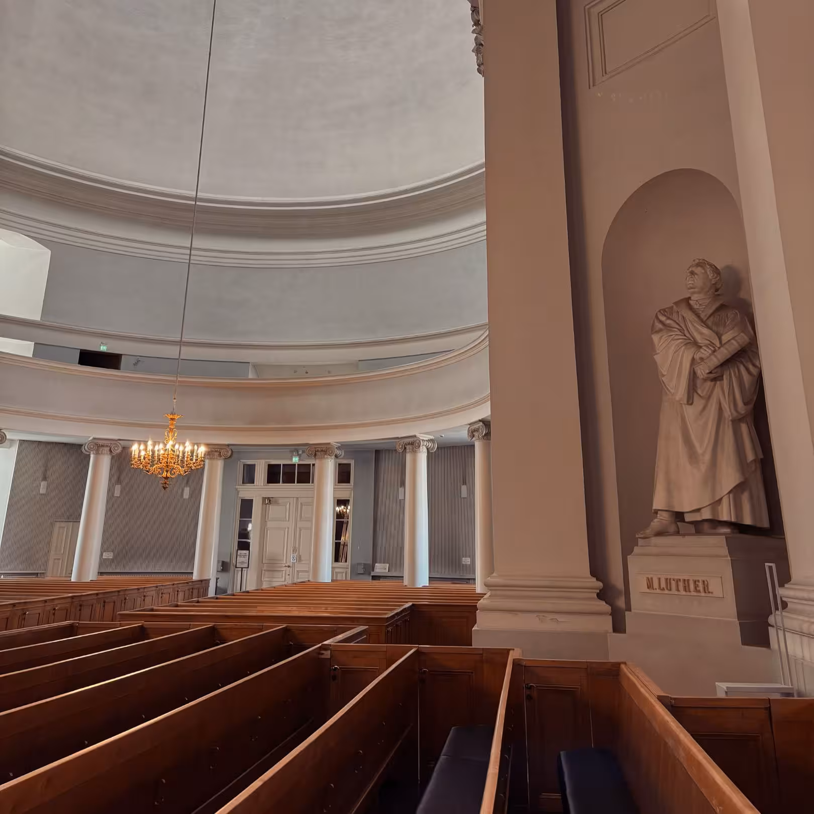 Interior of a historic church with wooden pews, columns, and a statue, ideal for an architecture tour experience.
