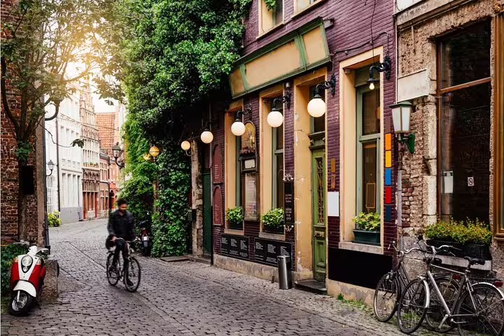 Cyclist riding through cobblestone street in historic Ghent city center with charming old buildings