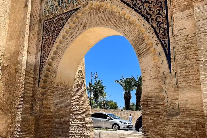 Historic stone archway with ornate carvings under a clear blue sky, located in the Old Medina of Fez.
