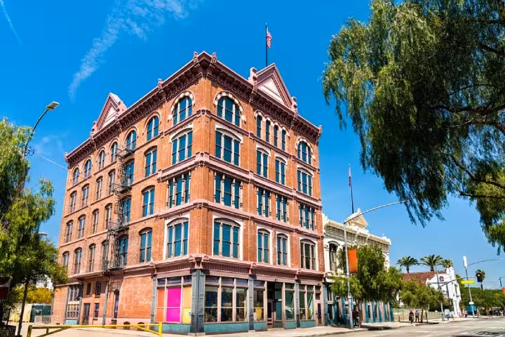 Historic red brick Victorian building on a street corner in downtown Los Angeles under blue sky