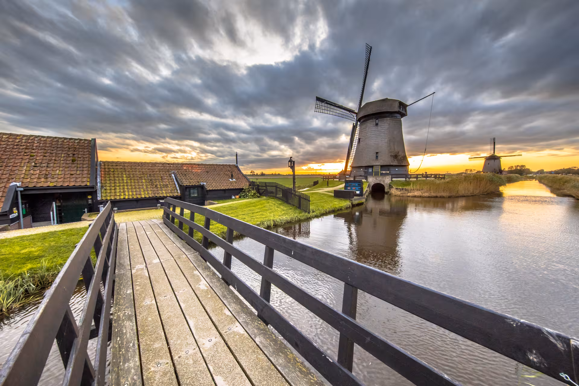 Historic windmill and wooden bridge over canal at sunset on private tour from Noordwijk, Dutch dikes tour