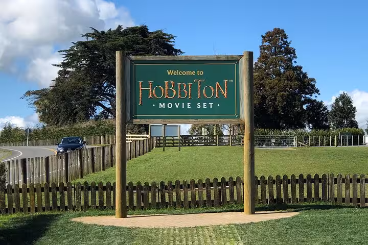 Welcome sign to Hobbiton Movie Set with lush greenery, perfect for a magical day tour experience.