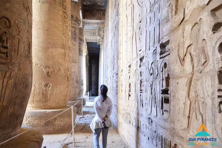 Traveler viewing ancient Egyptian hieroglyphs inside a temple corridor on 15 Days 14 Nights Holy Family Tour