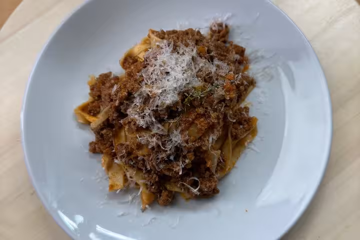 A plate of homemade pasta topped with rich meat sauce and grated cheese at the Italian cooking class in Barcelona.