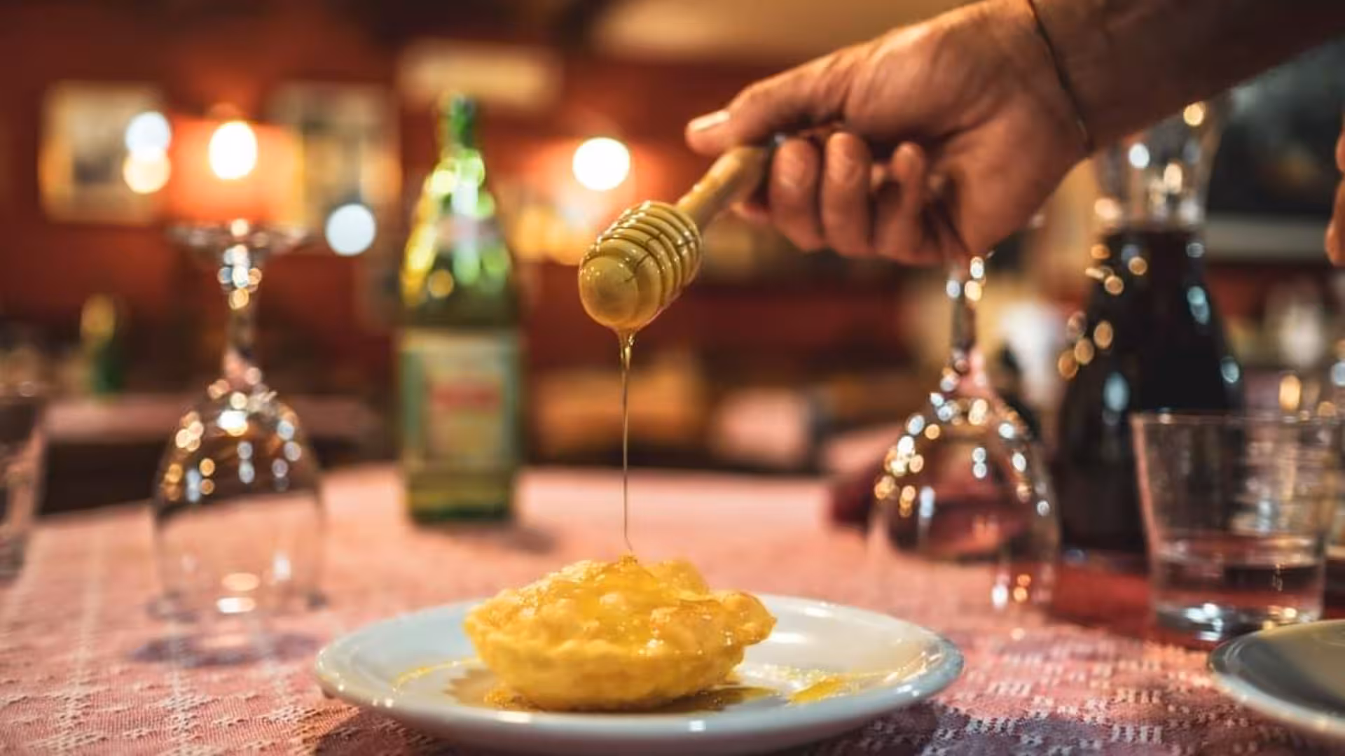 Close-up of honey drizzling over a freshly made seadas on a plate, capturing the essence of Bonorva's seadas workshop.