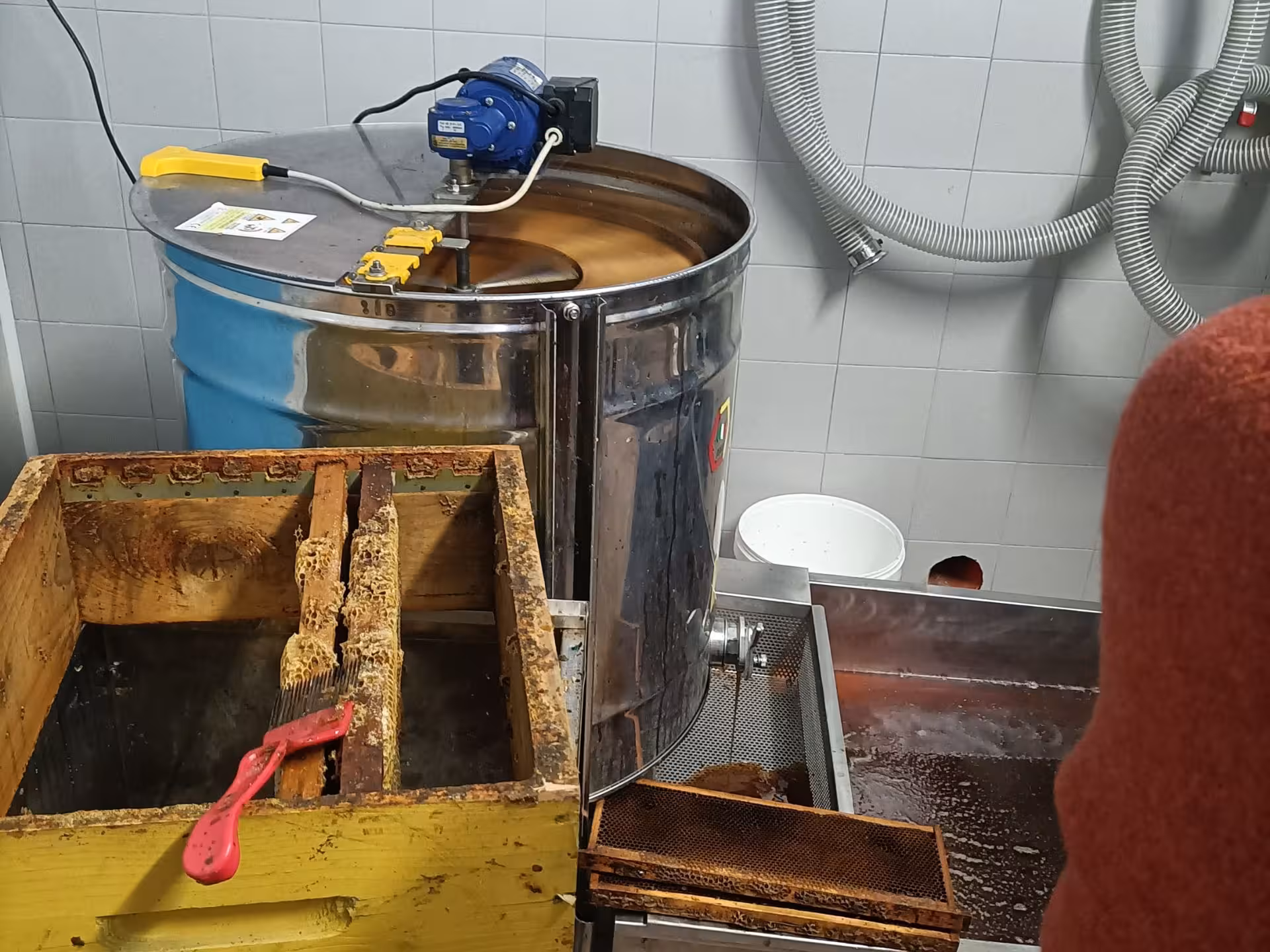 Honey extraction setup with equipment and honeycomb frames at Monferrato tasting experience.