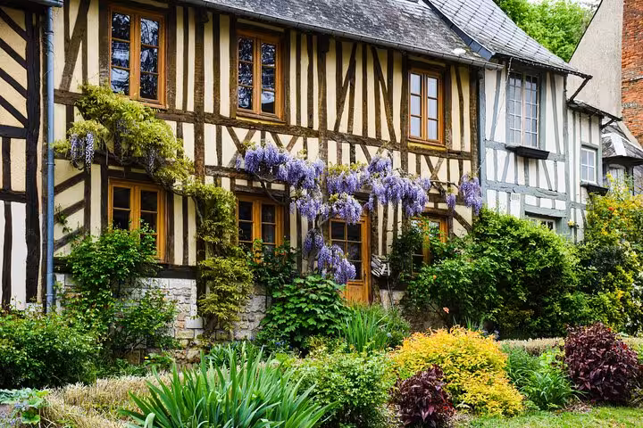 Half-timbered Norman house with purple wisteria and lush garden in Honfleur, Normandy