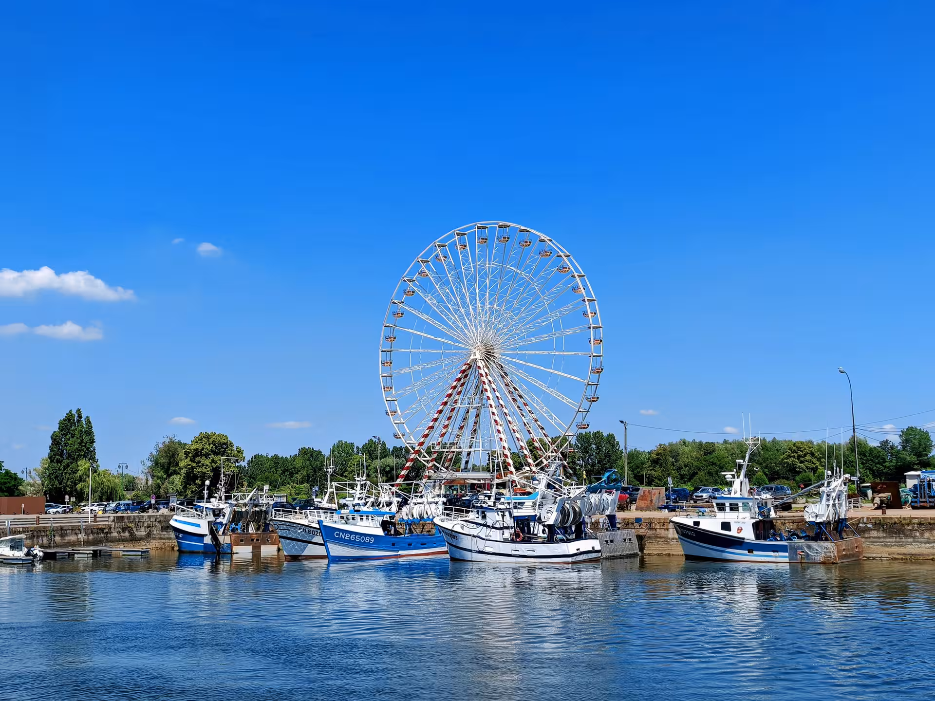 Honfleur harbor view with fishing boats and Ferris wheel, scenic stop on a private guided e-bike tour in Normandy