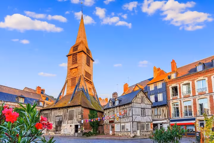 Honfleur town square with historic timber-framed buildings and the tall wooden bell tower of Saint-Étienne church