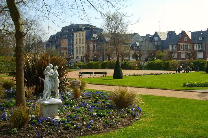 Classical statue in a French park garden with historic buildings and manicured lawns in Honfleur