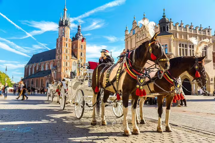 Horse-drawn white carriage in Krakow Main Square with St. Mary's Basilica in background