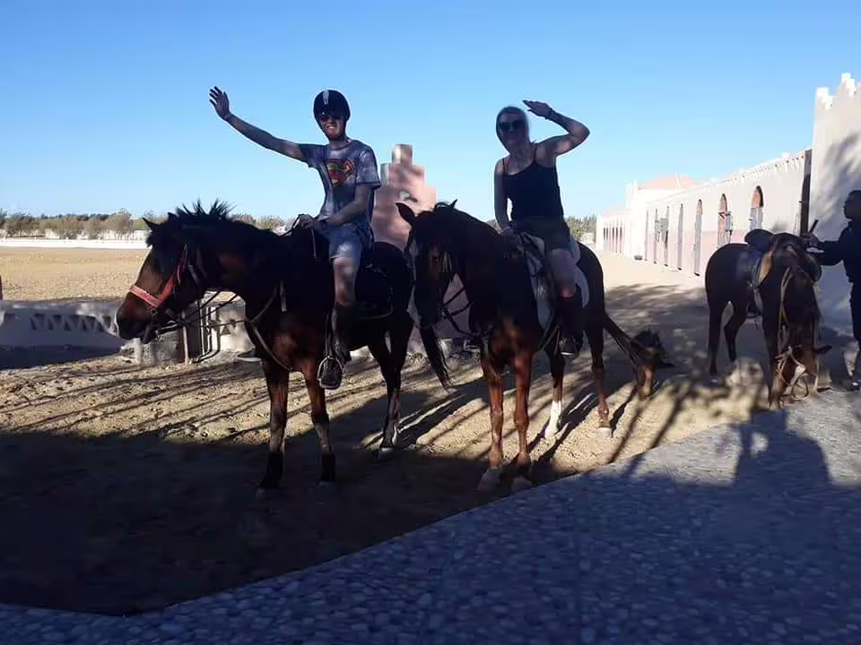 Tourists waving on horseback at Hurghada stable, part of Red Sea desert and beach horse riding excursion