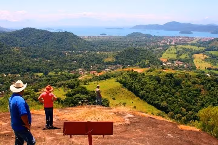 Tourists enjoy a panoramic view of Paraty from a hilltop, highlighting the Atlantic forest and coastal beauty.