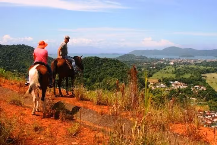 Horseback riders admire stunning vistas of the Atlantic forest and coastline from a scenic ridge near Paraty.