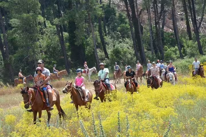 Tourists enjoy a horseback riding adventure through vibrant yellow fields and lush forests near Kusadasi Port.