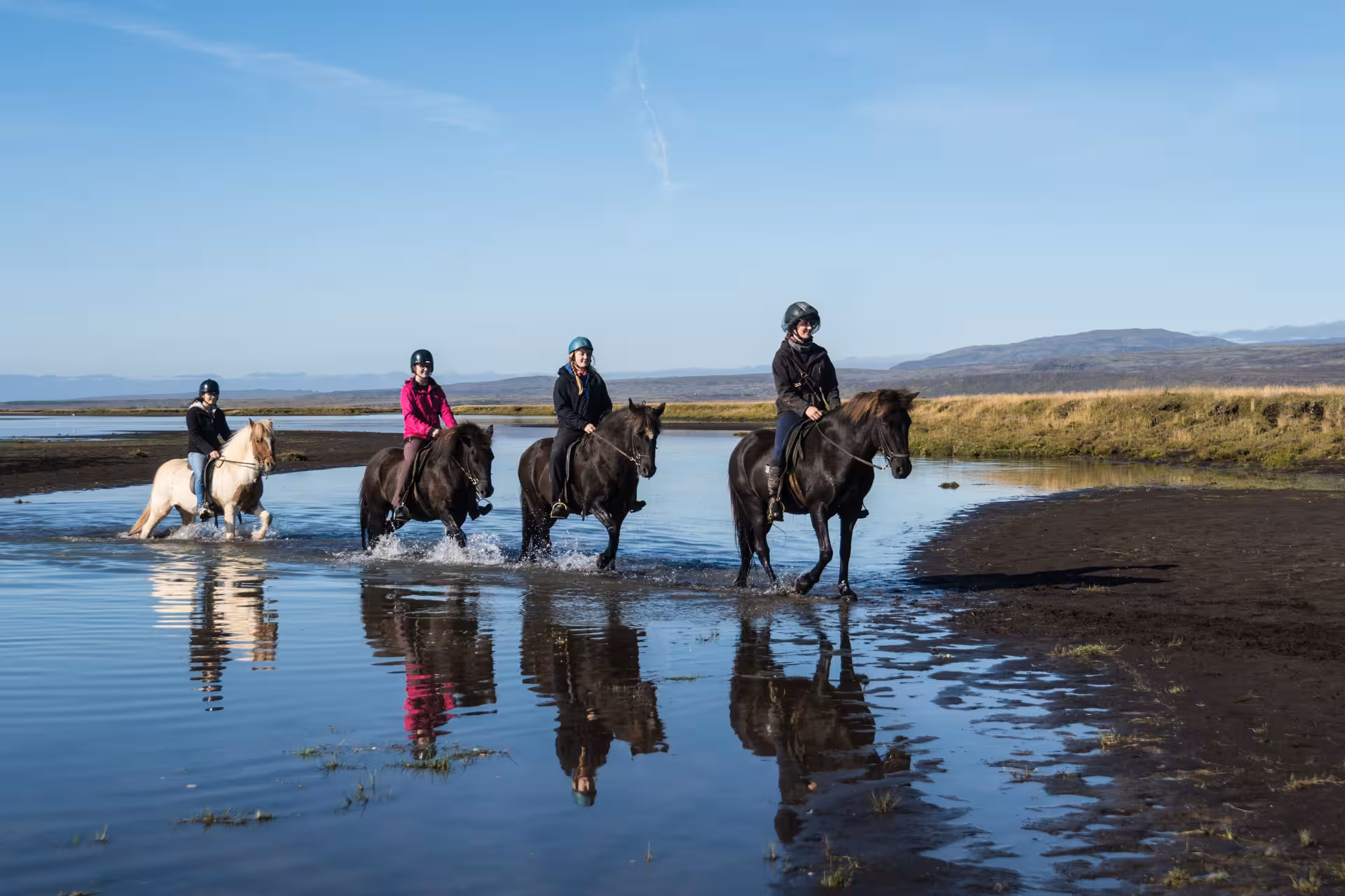 Small group horseback riding through shallow river water on the 03B Soft River Banks Iceland tour