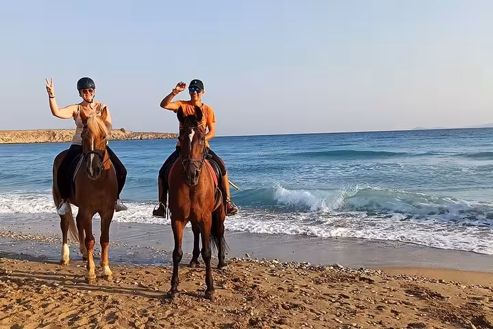 Two riders on horses posing on Hurghada shoreline with Red Sea waves during 3-hour swim with horses experience